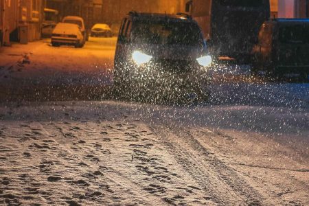 Auto rijdt door de nacht in de sneeuw
