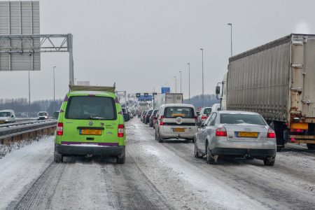Blik vanuit de auto over de met sneeuw bedekte snelweg, spitstrook gesloten.