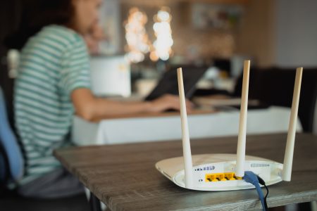 Wifi router en vrouw op laptop, daglicht