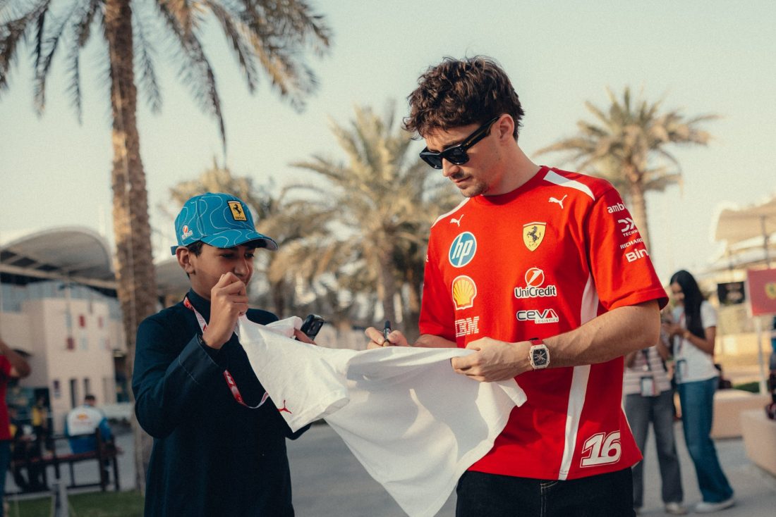 Charles Leclerc deelt een handtekening uit aan een jeugdige fan